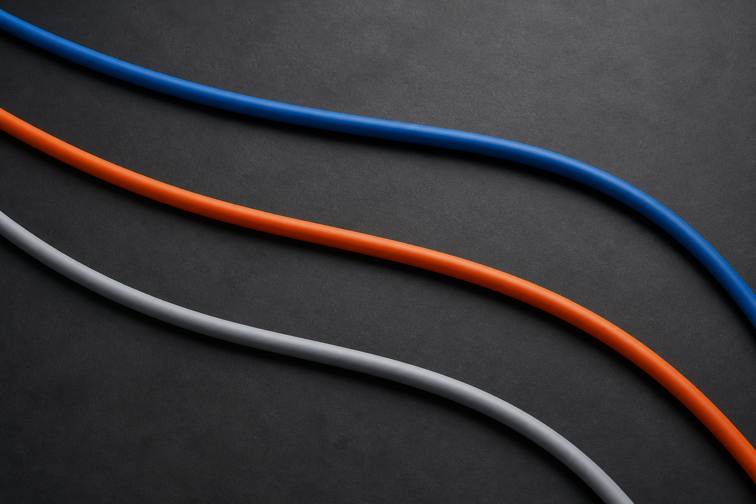 KI-generiertes Symbolbild: Drei geschwungene Kabel in Blau, Orange und Grau auf dunklem Grund.