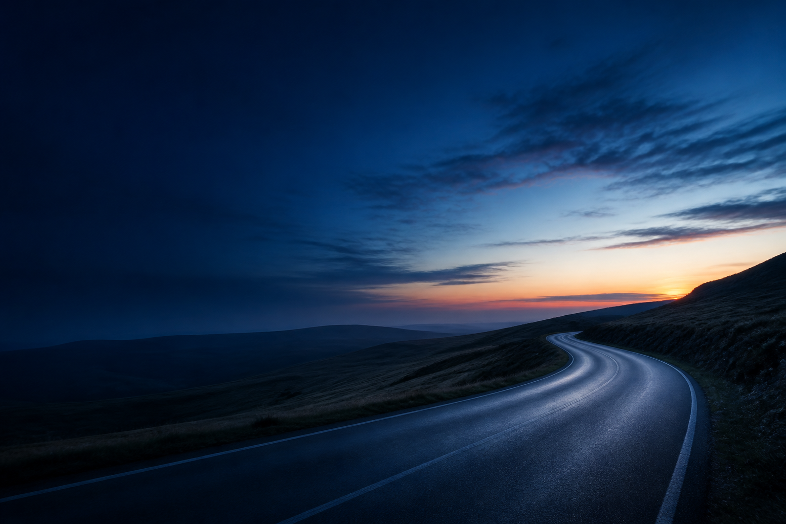 KI-generiertes Symbolbild: Eine leere, feucht glänzende Straße führt durch eine weite Hügellandschaft zum orangefarbenen Abendhorizont.